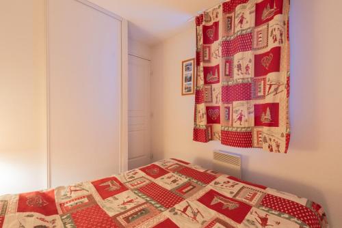 a bedroom with a bed with a quilt on the wall at T2 avec piscine couverte et parking in Saint-Lary-Soulan