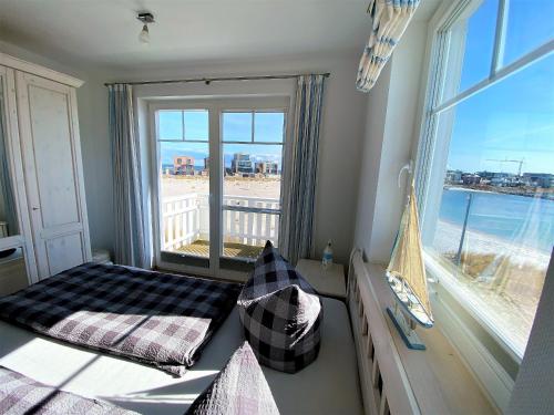 a bedroom with a view of the beach from a window at Strand Hus by Seeblick Ferien in Olpenitz