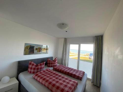 a bedroom with a bed with red and white pillows at Brigantine 33 by Seeblick Ferien in Olpenitz