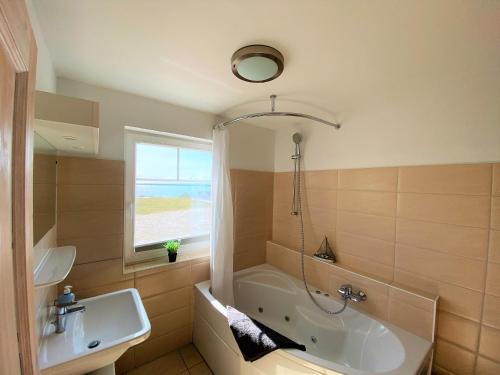 a bathroom with a tub and a sink at Strand Hus by Seeblick Ferien in Olpenitz