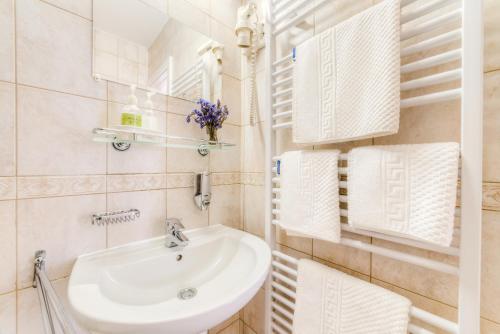 a white bathroom with a sink and towels at Kata Panzió in Szeged