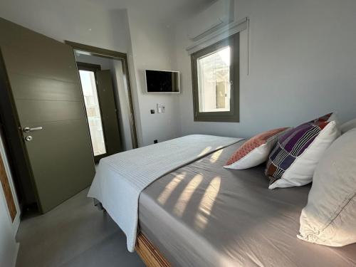 a bedroom with a bed with pillows and a window at Naousa Paros Suite B with private jacuzzi in Naousa
