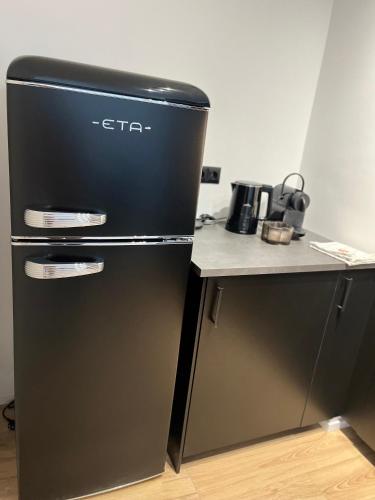 a black refrigerator in a kitchen next to a counter at Krušec apartmán Plešivec in Karlovy Vary