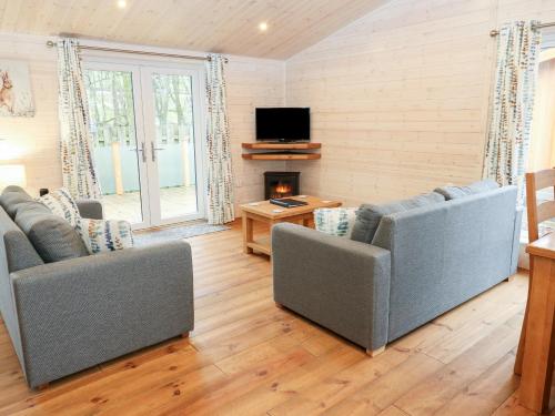 a living room with two couches and a television at Dovestone Secluded Luxury Lodges sleeps 6 - pets welcome in Oldham