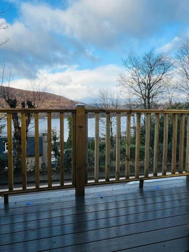 a wooden railing on a deck with mountains in the background at Plum Tree Pod in Fort William