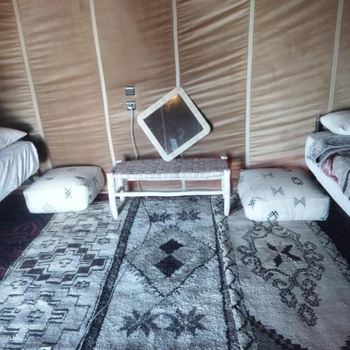 a room with a tv and a table and two beds at Touareg Desert Camp Erg Chigaga in El Gouera