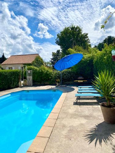 - une piscine bleue avec un parasol et des chaises bleus dans l'établissement Aux Agapanthes, Chambres d'Hôtes charentaises de charme avec piscine, à Aumagne