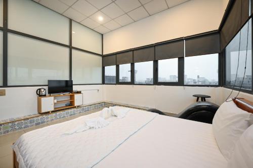 a bedroom with a large white bed with windows at Yoyo Airport Saigon Hotel in Ho Chi Minh City