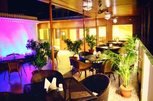 un restaurante con mesas, sillas y plantas en Hotel H R Palace en Jaipur