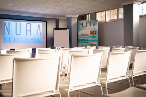 an empty room with white chairs and a screen at NURA Boreal in Playa de Palma