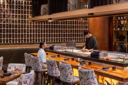 two people standing at a counter in a restaurant at Dusit Thani Manila in Manila