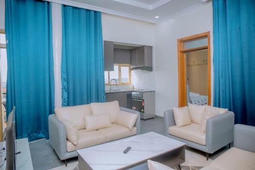 un soggiorno con 2 divani bianchi e tende blu di Mama's Favourite ltd a Kigali