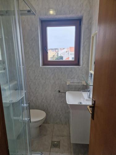 a bathroom with a toilet and a sink and a window at Apartments Katarina k in Malinska