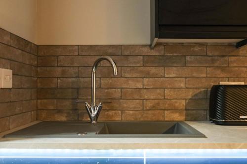 a kitchen sink with a faucet on a brick wall at The Willow - Studio 27 in Bristol