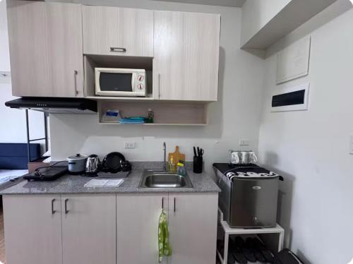 a small kitchen with a sink and a microwave at Tulip Garden Apricot Southwoods Binan 1BR with Pool & gym in Biñan