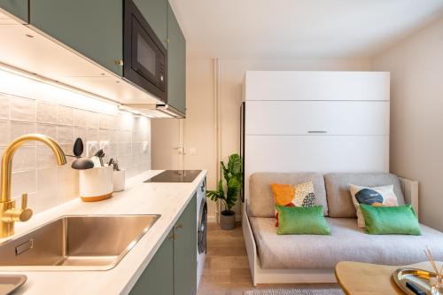 - une cuisine avec un canapé et des oreillers colorés dans l'établissement Stunning Tiny Studio - 5 min to Eiffel Tower - Sleeps 2P, à Paris