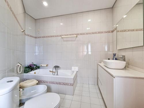 a white bathroom with a toilet and a sink at Casa Cogumelo Beachfront Retreat in Viana do Castelo