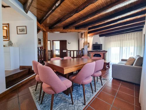 a dining room with a wooden table and pink chairs at Casa Cogumelo Beachfront Retreat in Viana do Castelo