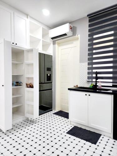 a kitchen with white cabinets and a black and white tile floor at Villa Ayer Keroh Swimming Pool by DefineSuite in Ayer Keroh