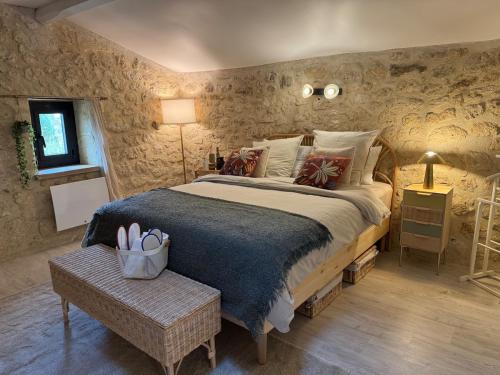 - une chambre avec un grand lit dans une pièce aux murs en pierre dans l'établissement La Maisonnette d'Émilion, à Naujan-et-Postiac