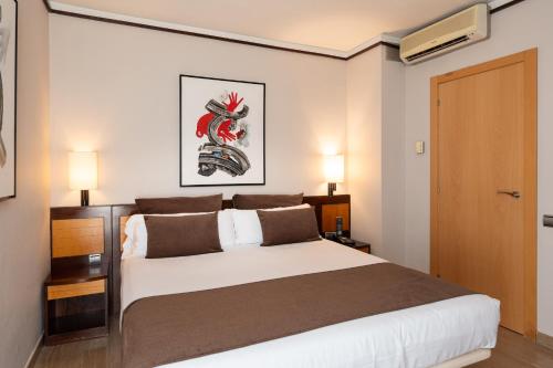 a bedroom with a large white bed and two lamps at Estela Barcelona in Sitges