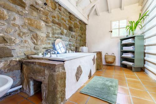La salle de bains est pourvue d'un mur en pierre et d'un lavabo. dans l'établissement Mendizola - 5 chambres - Piscine - Vue montagne, à Sare