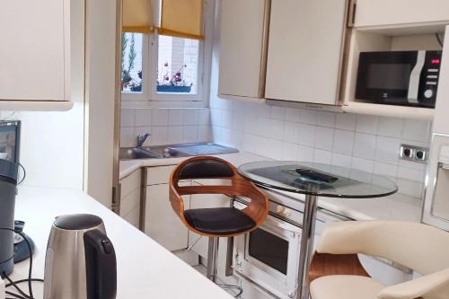 une petite cuisine avec une table et une chaise dans l'établissement Appartement cosy à Paris (Trocadéro) - 60 m² - ParkingEL, à Paris