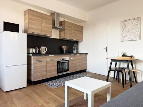 une cuisine avec un réfrigérateur blanc et une table dans l'établissement Appartement F2 coeur de Vichy bellle vue, à Vichy