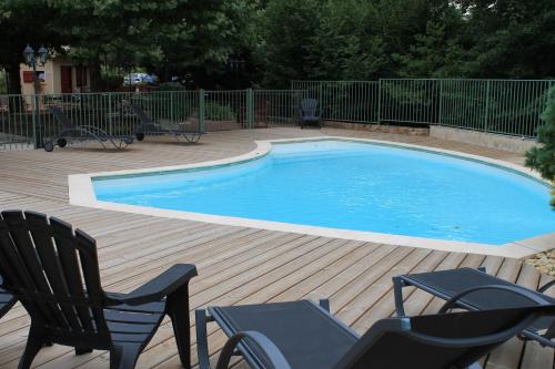 a swimming pool on a wooden deck with chairs around it at Hôtel Restaurant Le Moulin de Saint Verand in Saint-Vérand
