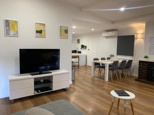 a living room with a television and a table with chairs at Lucky Charm Cottage in Manjimup