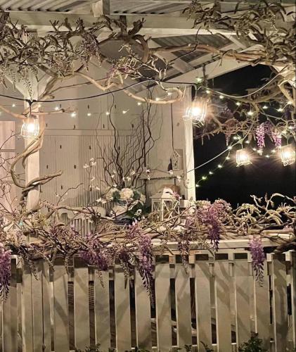 a white fence with purple flowers and lights at The Old Bakery in Historic Kangaroo Valley Village in Kangaroo Valley