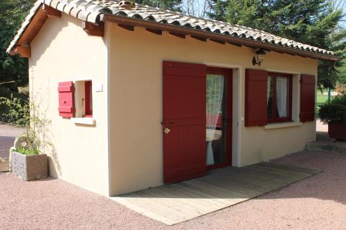 a small house with a red door and windows at Hôtel Restaurant Le Moulin de Saint Verand in Saint-Vérand