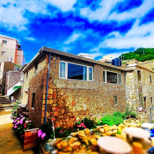 a stone building with a window and flowers at Horn Seaside Homestay in Nangan