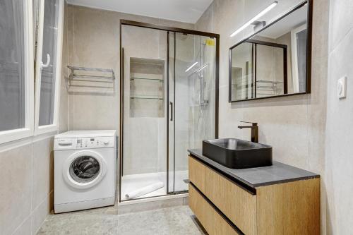 une salle de bain avec un lavabo et une machine à laver dans l'établissement Martine Suite, Place de la République, à Paris