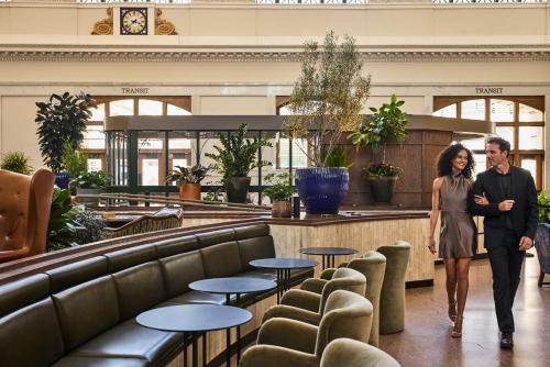 a man and a woman walking through a lobby at The Crawford Hotel in Denver