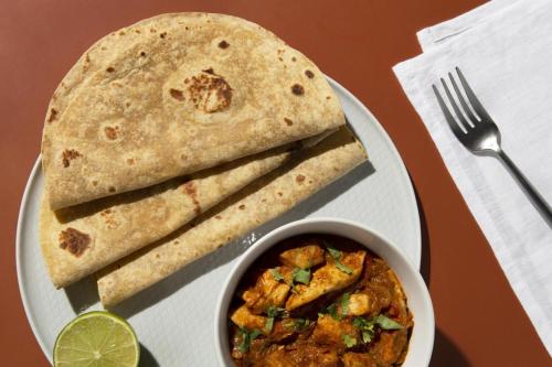 a plate of food with a bowl of curry and a tortilla at FabHotel Annapurna in McLeod Ganj