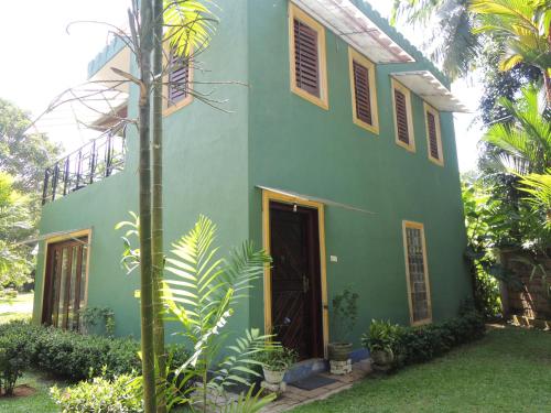 a green house with a tree in front of it at The Residence Bentota in Bentota