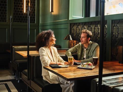 a man and woman sitting at a table in a restaurant at The Crawford Hotel in Denver