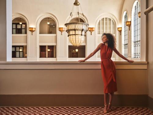 a woman in a red dress standing in front of a window at The Crawford Hotel in Denver