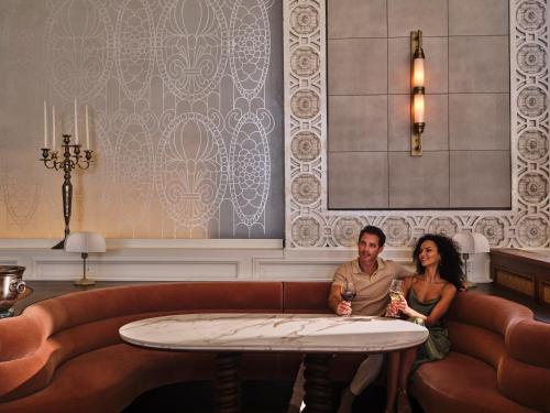 a man and a woman sitting on a couch at The Crawford Hotel in Denver