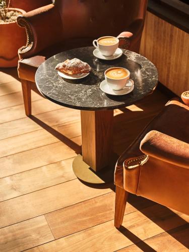 a coffee table with two cups of coffee and food on it at The Crawford Hotel in Denver