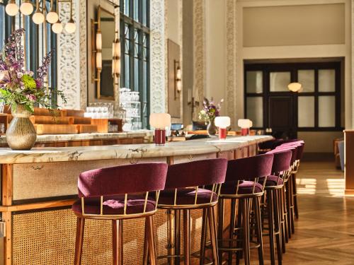 a bar with a row of purple bar stools at The Crawford Hotel in Denver