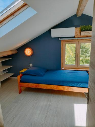 Ce lit se trouve dans un dortoir doté d'un mur bleu et d'une fenêtre. dans l'établissement La Maison du Plongeoir 14 pers grande terrasse vue lac de Serre Ponçon, à Savines