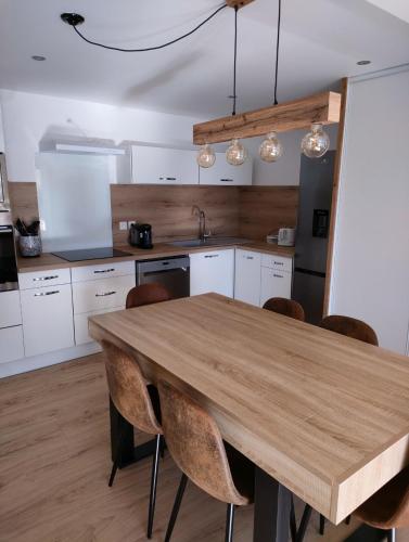 une cuisine avec une table et des chaises en bois dans l'établissement La Maison du Plongeoir 14 pers grande terrasse vue lac de Serre Ponçon, à Savines