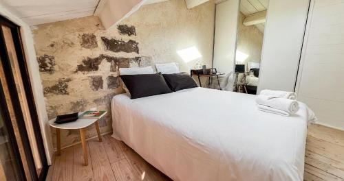 une chambre avec un lit blanc et un mur en pierre dans l'établissement AC - Rooftop views - Festival heart, à Avignon