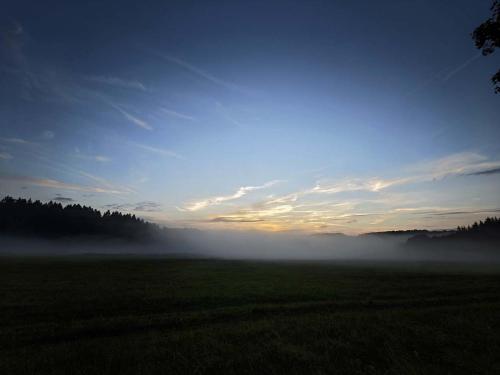 a foggy field with the sun rising in the sky at Chata pro dva nebo pro celou rodinu in Slavníč