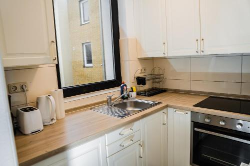 a kitchen with white cabinets and a sink and a window at Cozy and central Apartment Lübeck in Lübeck