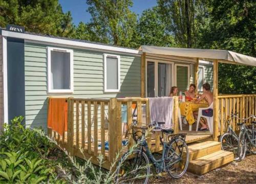 a green tiny house with people sitting on the porch at ZEcamping chiens acceptés espace aquatique et bar in La Baule