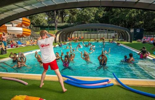 a man standing in a swimming pool with a crowd of people at ZEcamping chiens acceptés espace aquatique et bar in La Baule