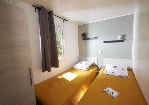 une petite chambre avec deux lits et une fenêtre dans l'établissement Camping - Parc aquatique - ccagehb, à Saint-Michel-Chef-Chef